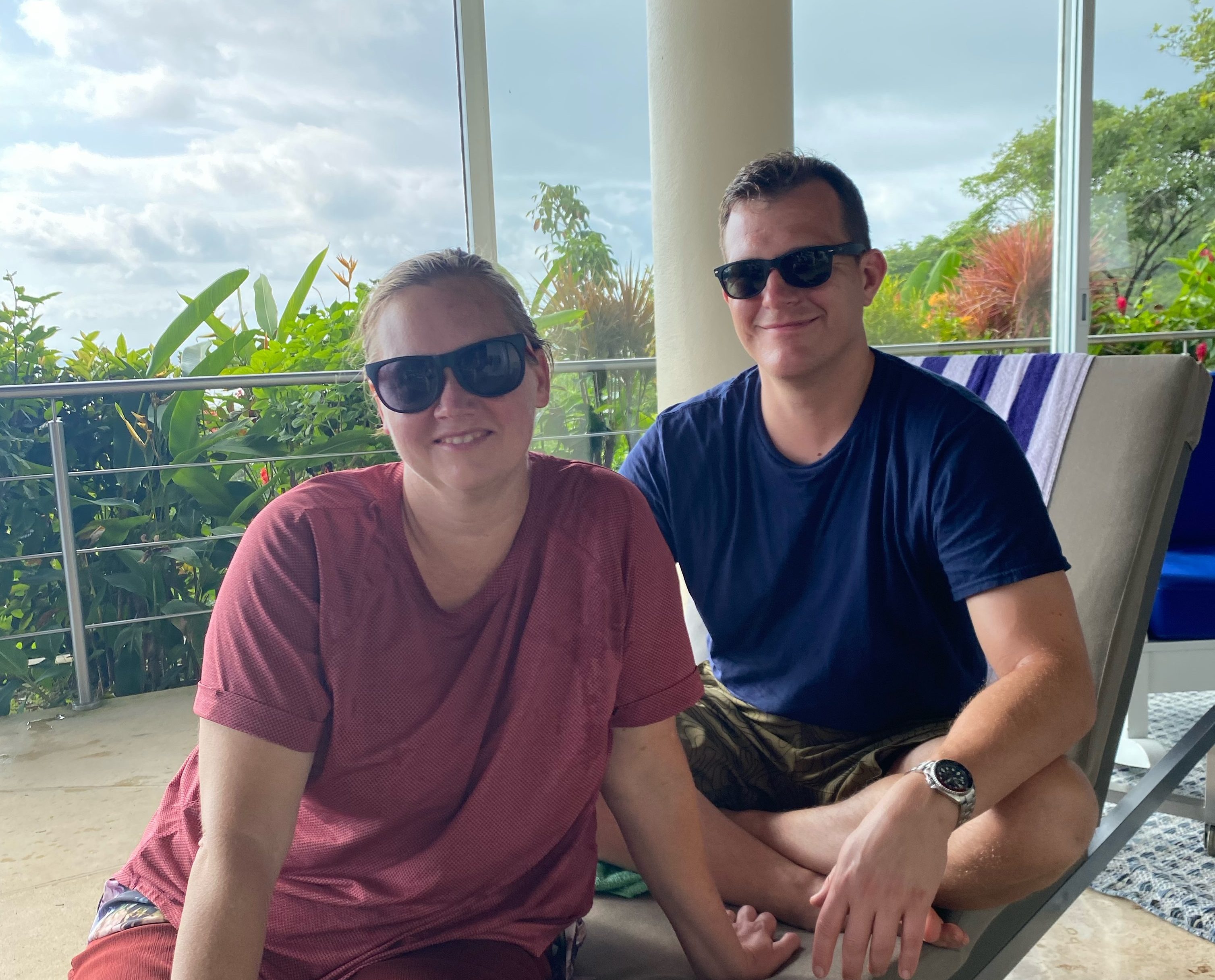 A picture of a married couple relaxing on a chair in a tropical location.